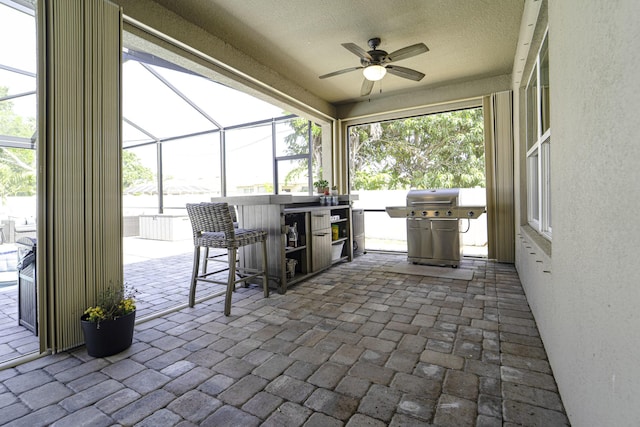 view of patio / terrace featuring a ceiling fan, glass enclosure, a grill, and outdoor dry bar