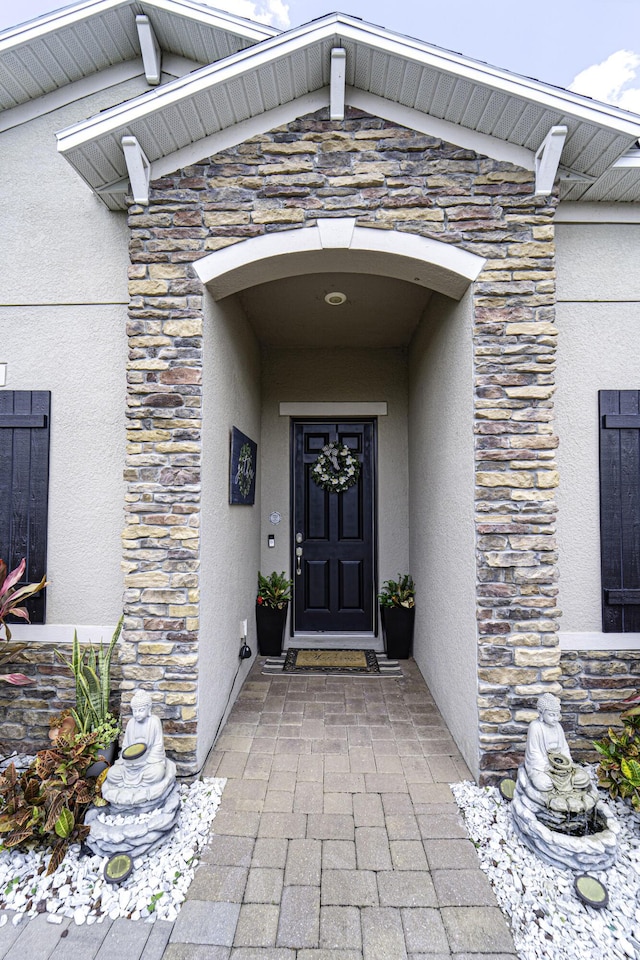 property entrance featuring stone siding and stucco siding
