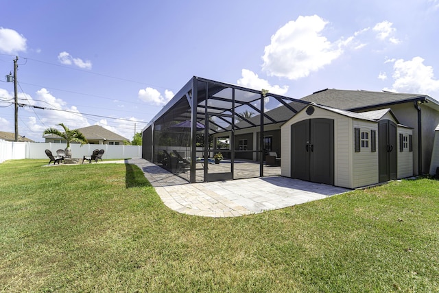 back of property featuring an outdoor structure, a storage unit, a patio, a fenced backyard, and a lawn