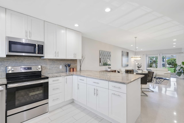 701 NE Harbour Ter Unit 103, Boca Raton, FL 33431 - kitchen with appliances with stainless steel finishes, a peninsula, white cabinets, open floor plan, and backsplash