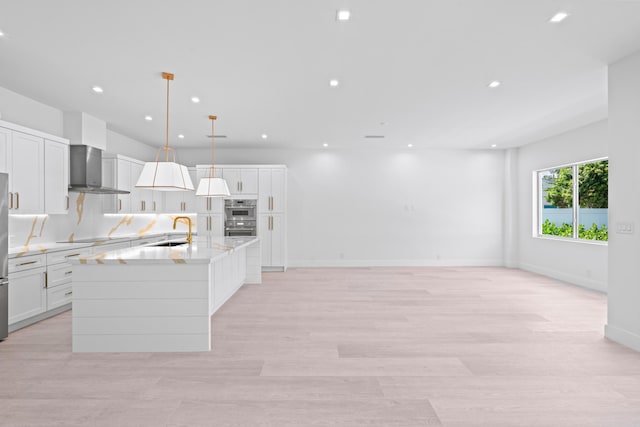 126 Auburn Dr, Lake Worth Beach, FL 33460 - kitchen featuring a sink, a kitchen island with sink, double oven, wall chimney exhaust hood, and white cabinets