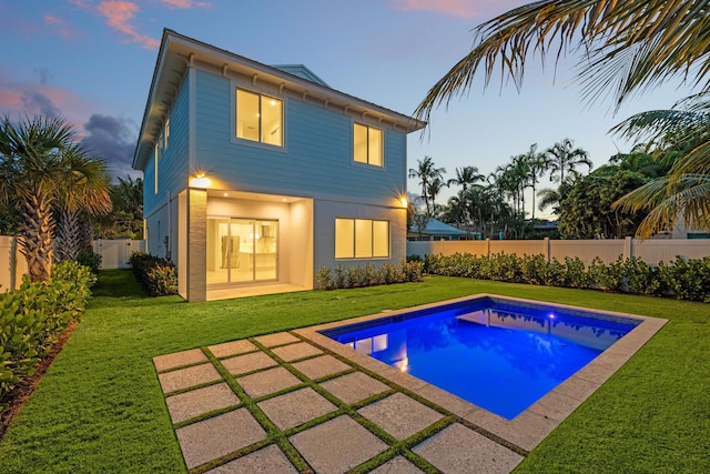 126 Auburn Dr, Lake Worth Beach, FL 33460 - back of house at dusk featuring a yard, a patio, and a fenced in pool