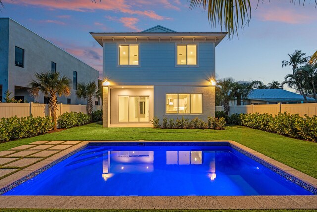 126 Auburn Dr, Lake Worth Beach, FL 33460 - back of property at dusk with a lawn, a fenced in pool, and a fenced backyard