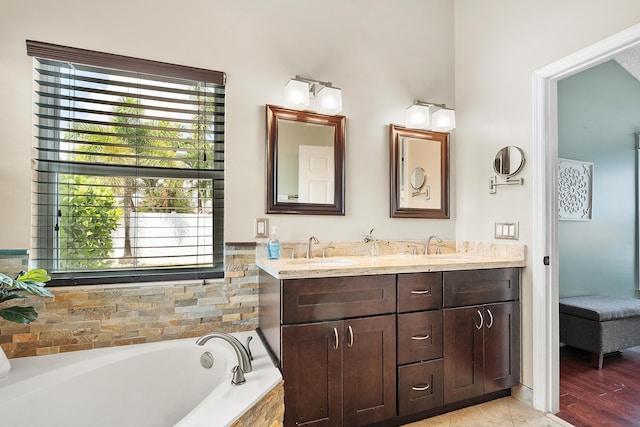bathroom featuring a sink, double vanity, and a garden tub