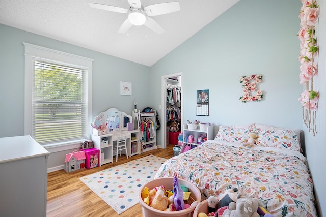bedroom with a closet, wood finished floors, ceiling fan, a walk in closet, and baseboards