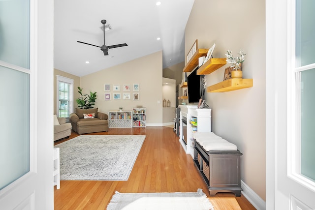 interior space with ceiling fan, a glass covered fireplace, light wood-style floors, vaulted ceiling, and recessed lighting
