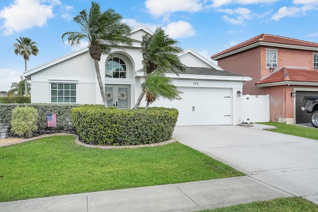 mediterranean / spanish-style home with fence, an attached garage, driveway, stucco siding, and a front yard