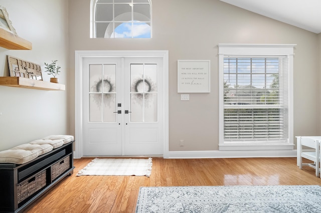 foyer with light wood-style flooring, baseboards, and high vaulted ceiling