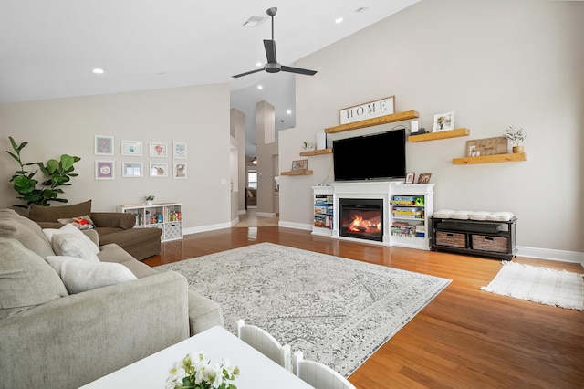 living area featuring baseboards, high vaulted ceiling, ceiling fan, and wood finished floors