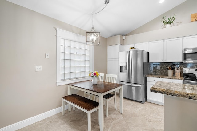 kitchen with an inviting chandelier, white cabinets, backsplash, appliances with stainless steel finishes, and lofted ceiling