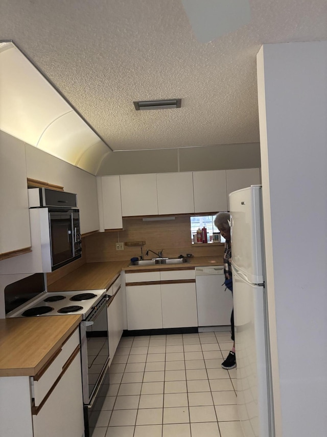 10137 Mangrove Dr Unit 203, Boynton Beach, FL 33437 - kitchen with a sink, white appliances, a textured ceiling, light tile patterned floors, and white cabinets