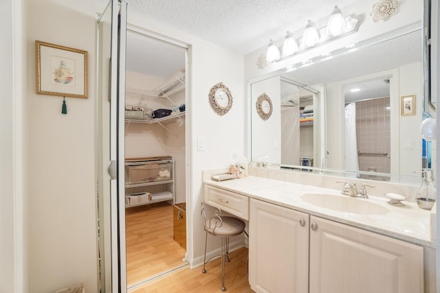 14360 Strathmore Ln Unit 404, Delray Beach, FL 33446 - bathroom featuring a textured ceiling, a shower with shower curtain, vanity, a walk in closet, and wood finished floors