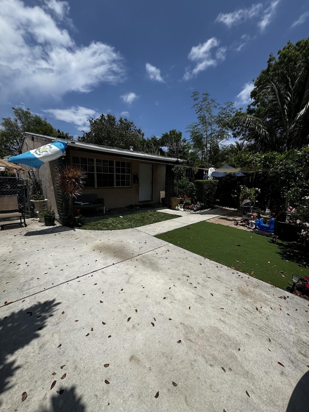 back of property featuring a yard, driveway, stucco siding, and a patio area