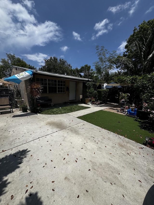 back of property featuring a yard, driveway, stucco siding, and a patio area