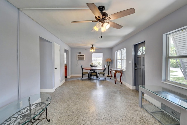 dining space with a wall mounted air conditioner, dark speckled floor, ceiling fan, and baseboards