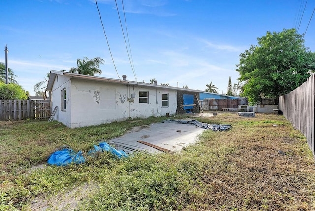 rear view of property featuring stucco siding, a fenced backyard, and a patio