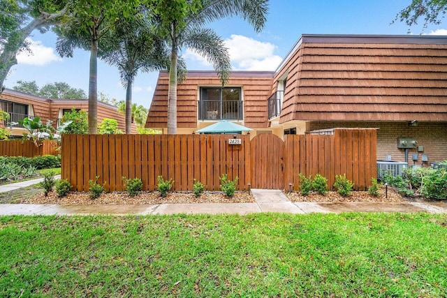 view of yard featuring central air condition unit, a fenced front yard, and a gate