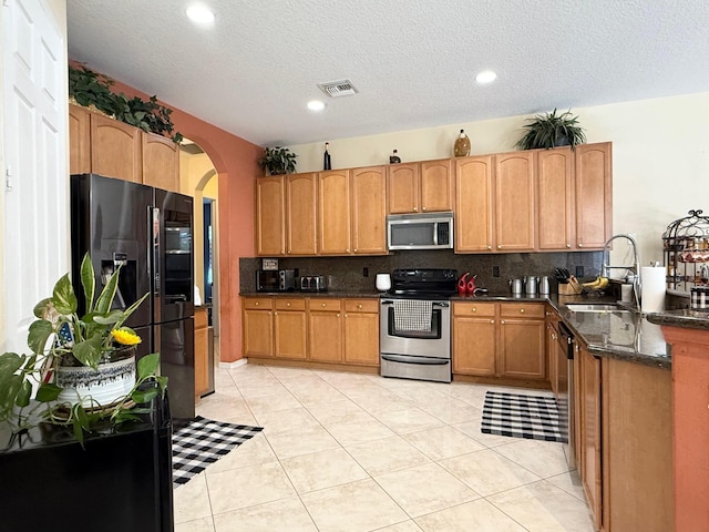 kitchen featuring a sink, visible vents, arched walkways, appliances with stainless steel finishes, and tasteful backsplash