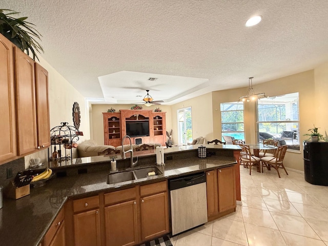 kitchen featuring dishwasher, brown cabinetry, open floor plan, and a sink