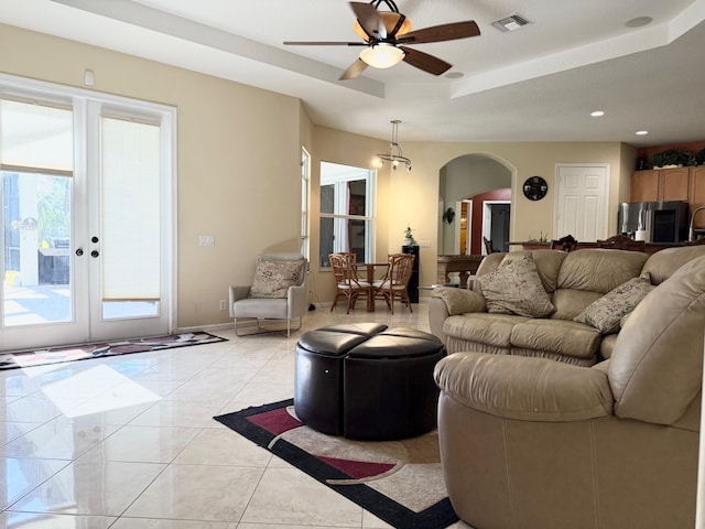 living room featuring visible vents, a raised ceiling, ceiling fan, arched walkways, and recessed lighting