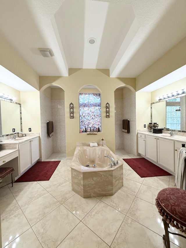 full bathroom featuring two vanities, a jetted tub, tile patterned flooring, and a sink