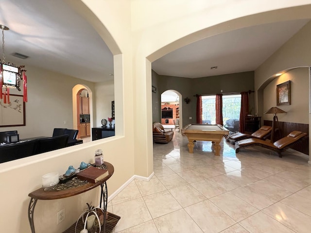 hall featuring light tile patterned flooring and arched walkways