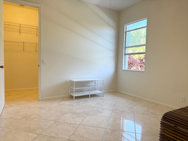 unfurnished room with light tile patterned floors and baseboards