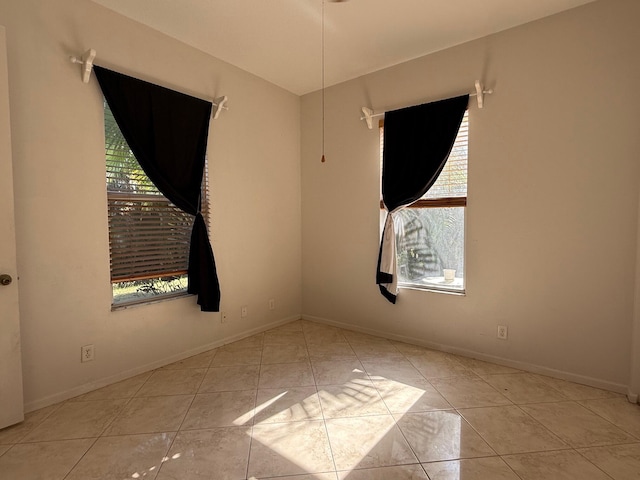 empty room featuring baseboards, a wealth of natural light, and tile patterned flooring