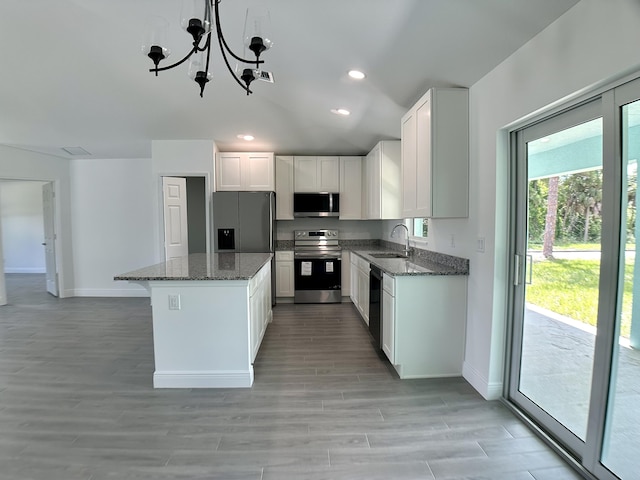 kitchen featuring dark stone counters, stainless steel appliances, baseboards, and a sink
