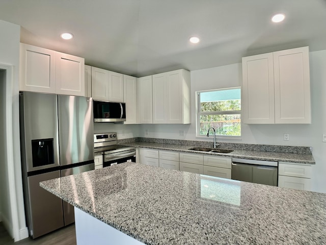 kitchen featuring a sink, white cabinets, appliances with stainless steel finishes, light stone counters, and recessed lighting