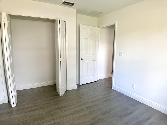 unfurnished bedroom featuring a closet, visible vents, baseboards, and dark wood-type flooring