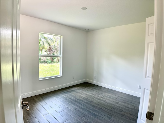 unfurnished room featuring baseboards and dark wood finished floors