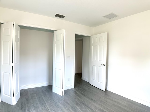 unfurnished bedroom with baseboards, dark wood-type flooring, and visible vents