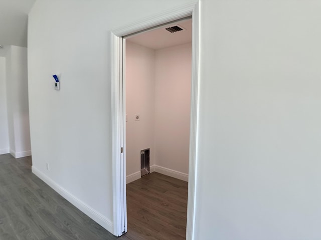 corridor featuring baseboards, visible vents, and wood finished floors