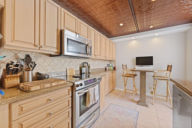 730 Greensward Ct Unit 203J, Delray Beach, FL 33445 - kitchen with stainless steel appliances, an ornate ceiling, tasteful backsplash, light tile patterned floors, and light brown cabinetry