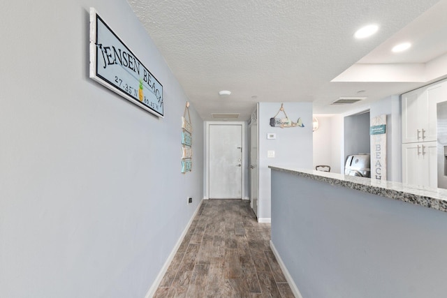 corridor with baseboards, dark wood-style flooring, washer / clothes dryer, and a textured ceiling