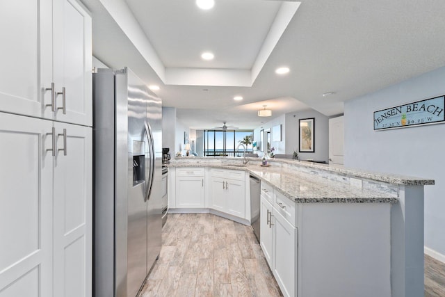 kitchen with stainless steel appliances, light stone counters, recessed lighting, light wood-style flooring, and white cabinetry