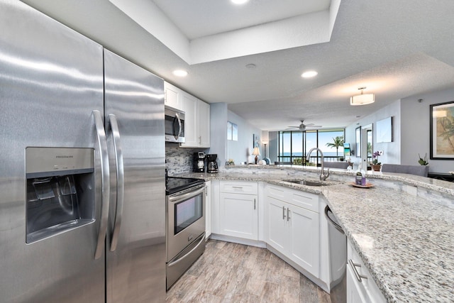 kitchen with a sink, white cabinetry, light stone countertops, appliances with stainless steel finishes, and recessed lighting