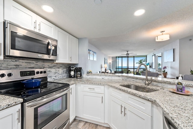 kitchen featuring a sink, stainless steel appliances, a textured ceiling, ceiling fan, and backsplash
