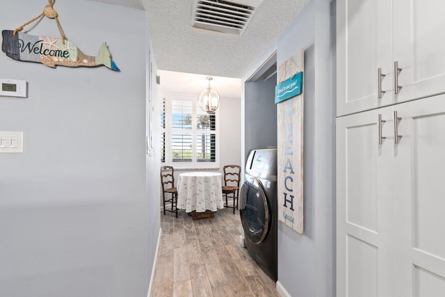 laundry room featuring light wood-style flooring, a textured ceiling, visible vents, washer / dryer, and a chandelier