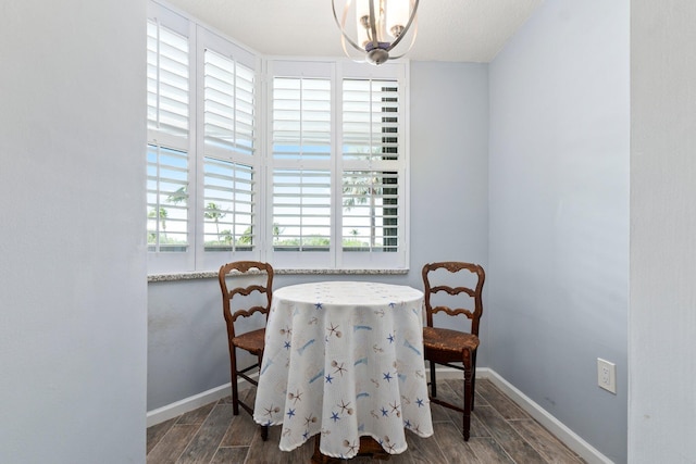 dining space with an inviting chandelier, wood finished floors, and baseboards