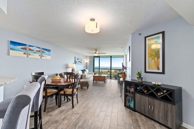 dining space with a textured ceiling, expansive windows, wood finished floors, and a ceiling fan