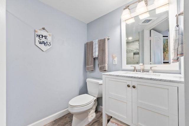 bathroom featuring toilet, wood finished floors, vanity, visible vents, and baseboards