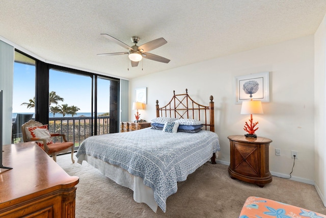 carpeted bedroom featuring expansive windows, a textured ceiling, baseboards, ceiling fan, and access to outside