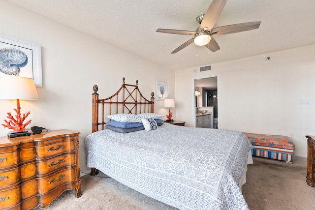 carpeted bedroom featuring a ceiling fan, ensuite bathroom, and visible vents