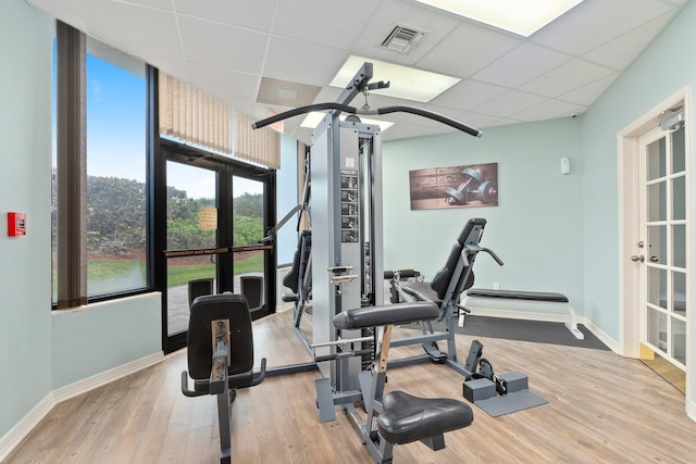exercise room with baseboards, a paneled ceiling, french doors, and expansive windows