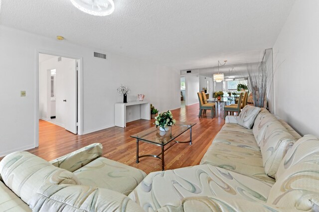 15244 Lakes Of Delray Blvd Unit 203, Delray Beach, FL 33484 - living room featuring a textured ceiling, wood finished floors, and a chandelier