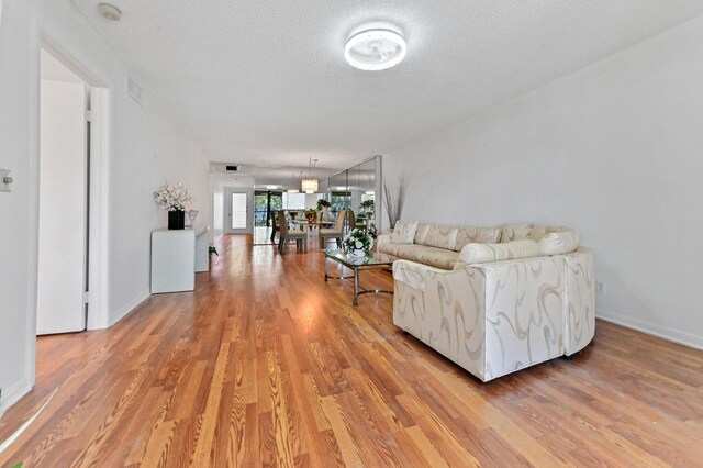 15244 Lakes Of Delray Blvd Unit 203, Delray Beach, FL 33484 - living room with light wood-style floors, a textured ceiling, and baseboards