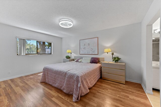15244 Lakes Of Delray Blvd Unit 203, Delray Beach, FL 33484 - bedroom featuring wood finished floors, a textured ceiling, baseboards, and ensuite bathroom
