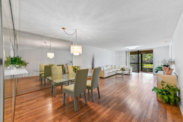15244 Lakes Of Delray Blvd Unit 203, Delray Beach, FL 33484 - dining room featuring a textured ceiling, wood finished floors, and a chandelier